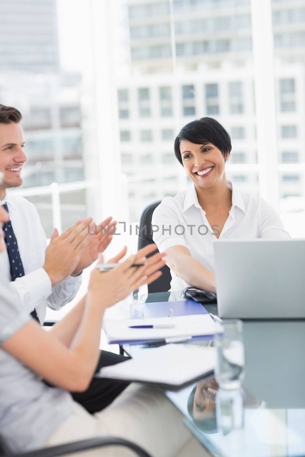 Young well dressed business people clapping while in a meeting at bright office