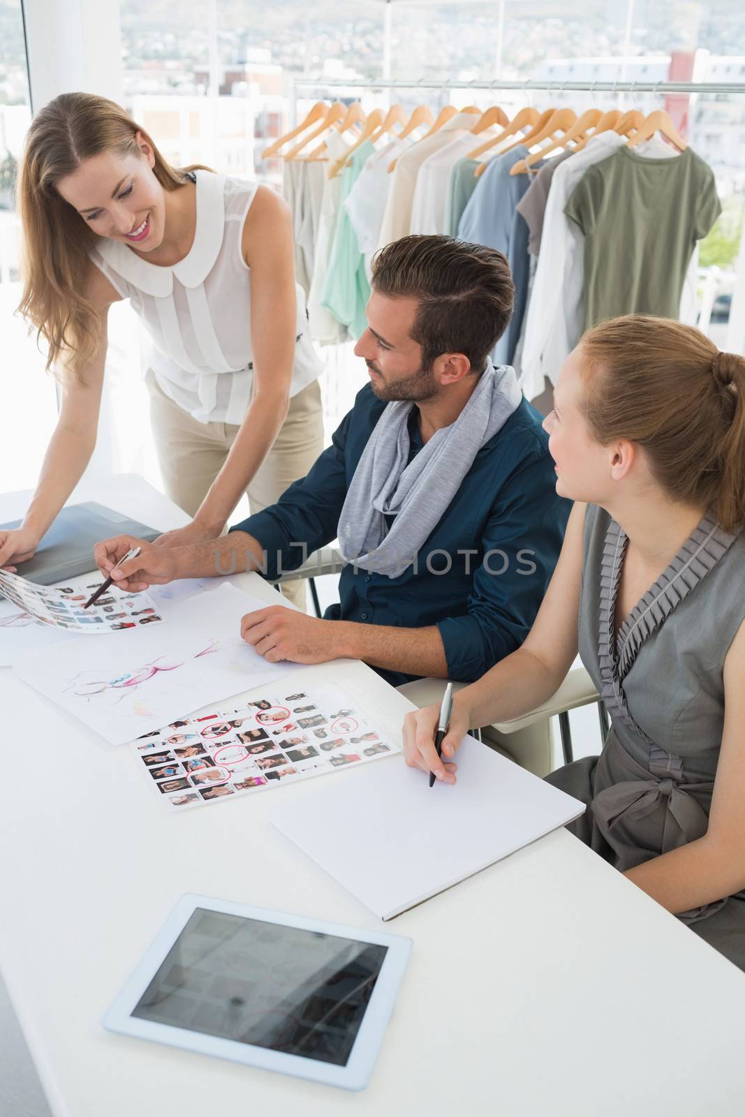 Three fashion designers discussing designs in a studio