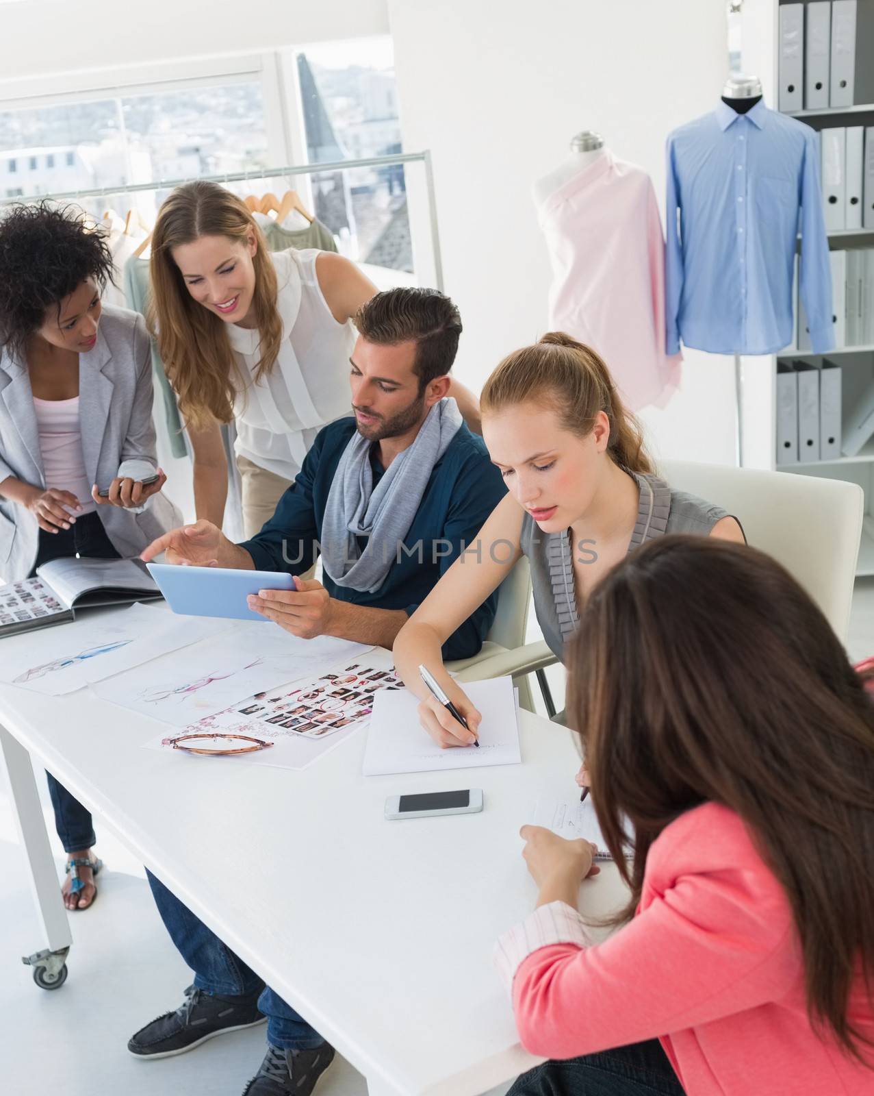 Group of fashion designers discussing designs in a studio