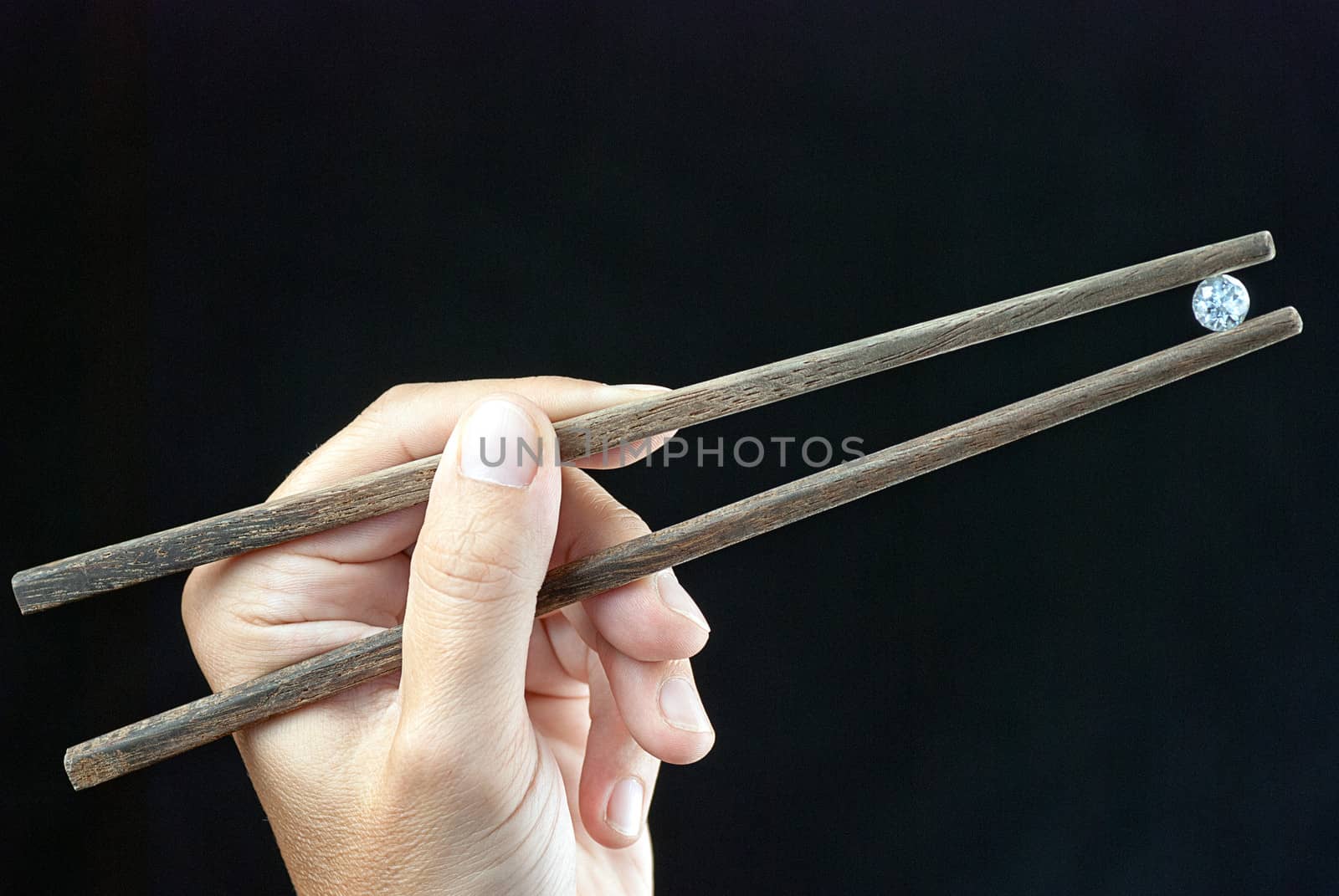 Close-up of a hand holding a gem using chopsticks.