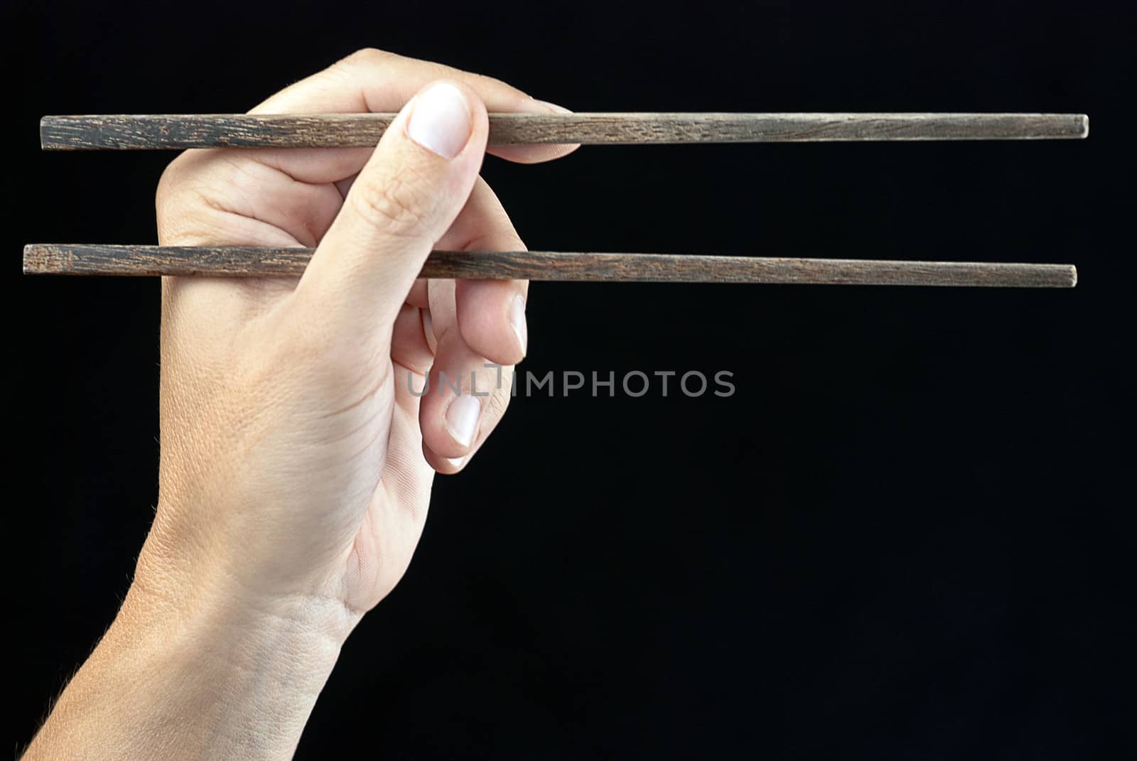 Close-up of a hand holding chopsticks.