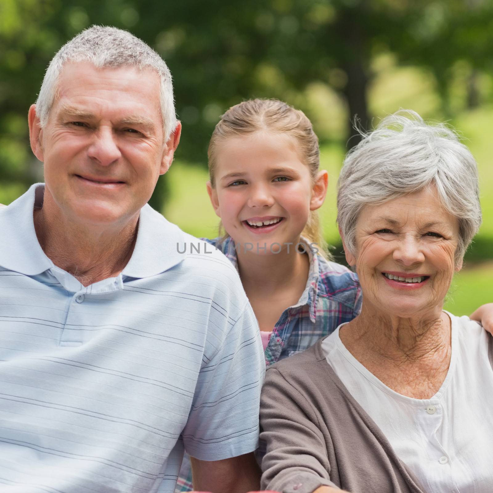 Smiling senior couple and granddaughter at park by Wavebreakmedia