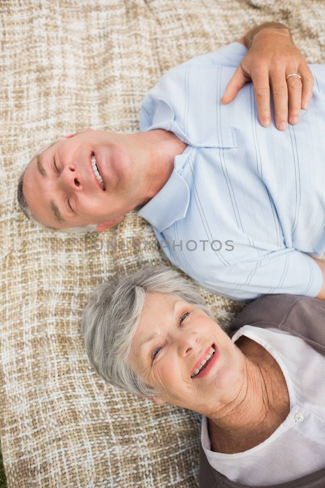 Smiling relaxed senior couple lying in park by Wavebreakmedia