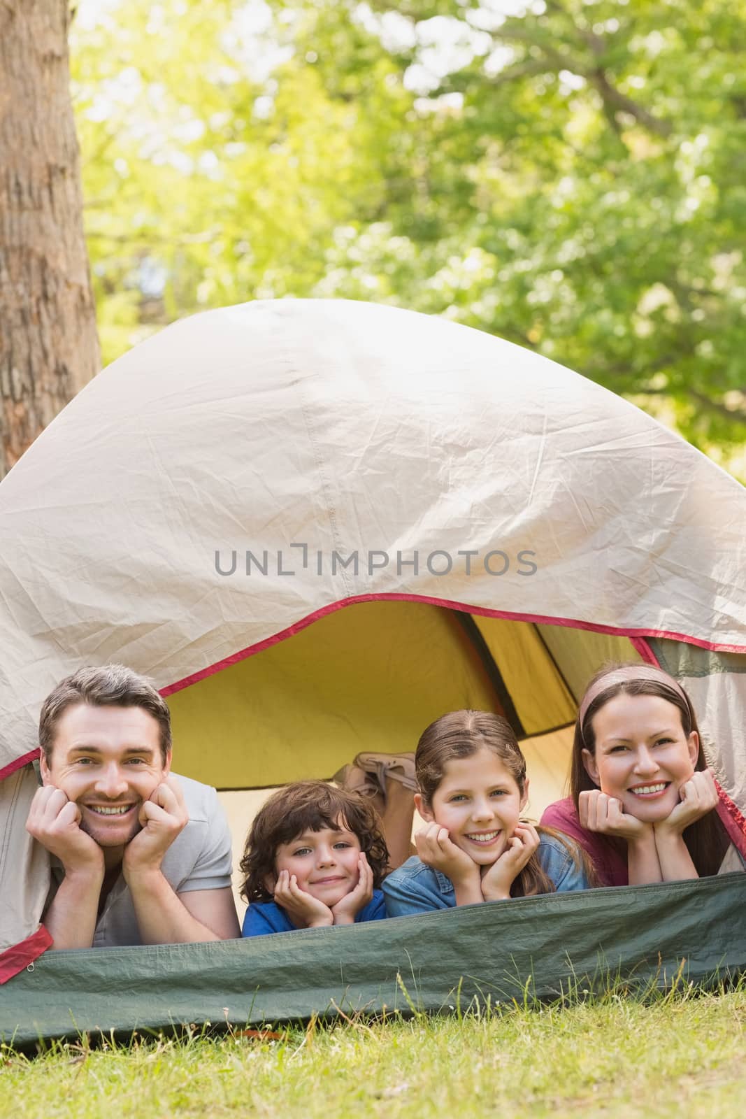 Couple with kids lying in the tent at park by Wavebreakmedia