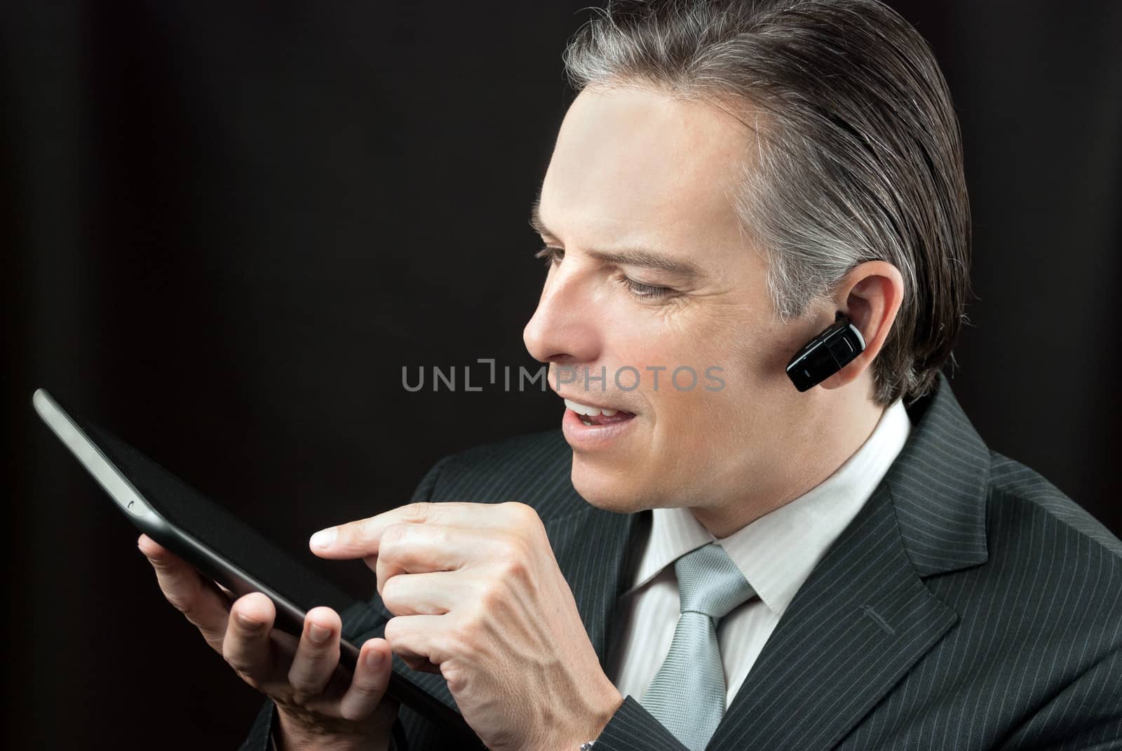 Close-up of a businessman wearing an earpiece headset using a tablet.
