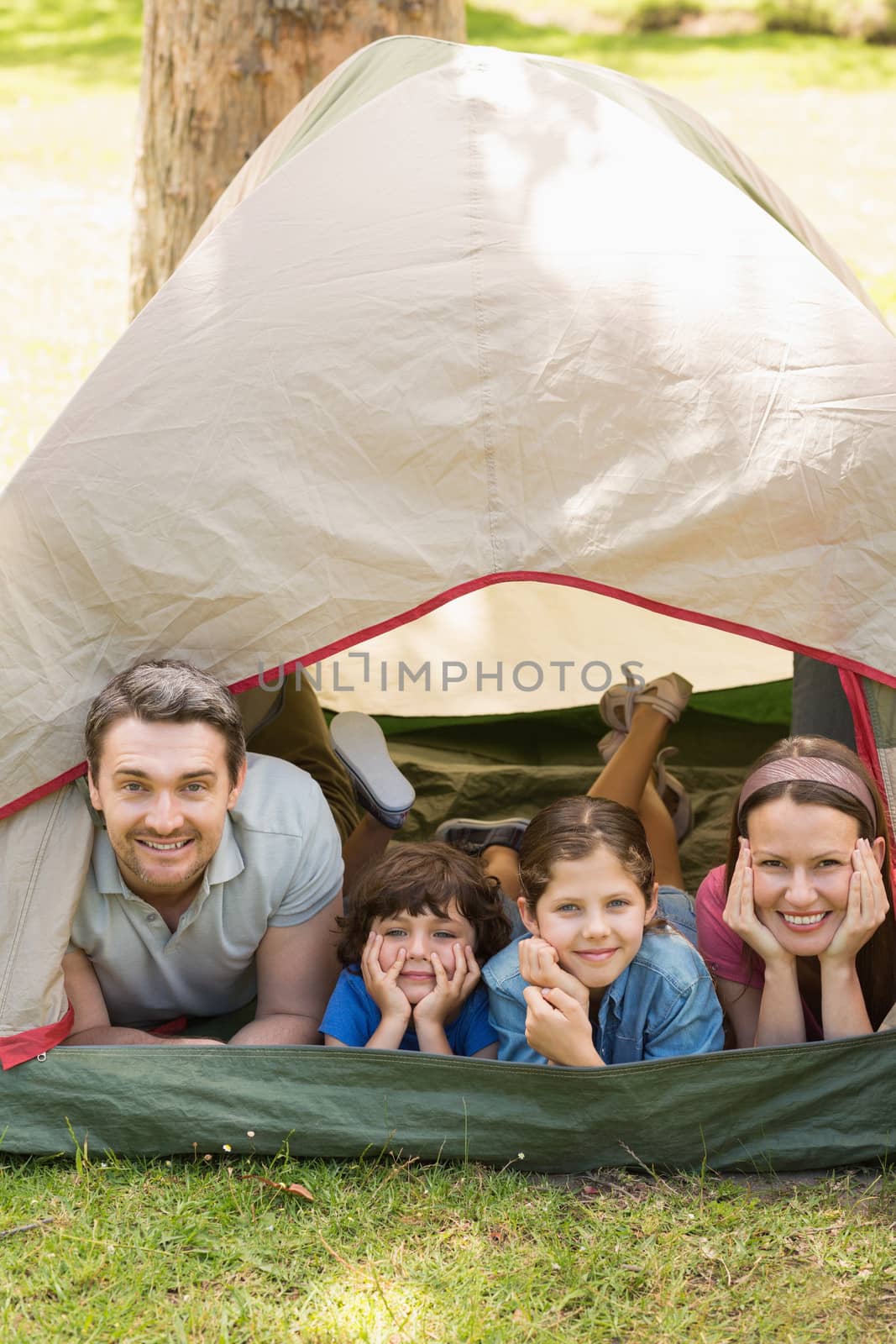 Portrait of couple with kids lying in the tent at park
