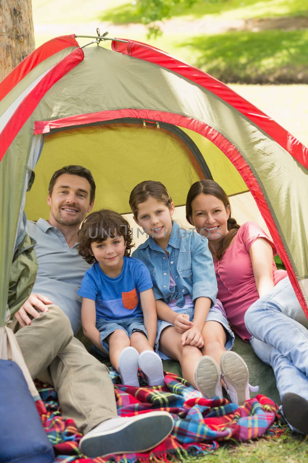 Portrait of couple with kids sitting in the tent at park