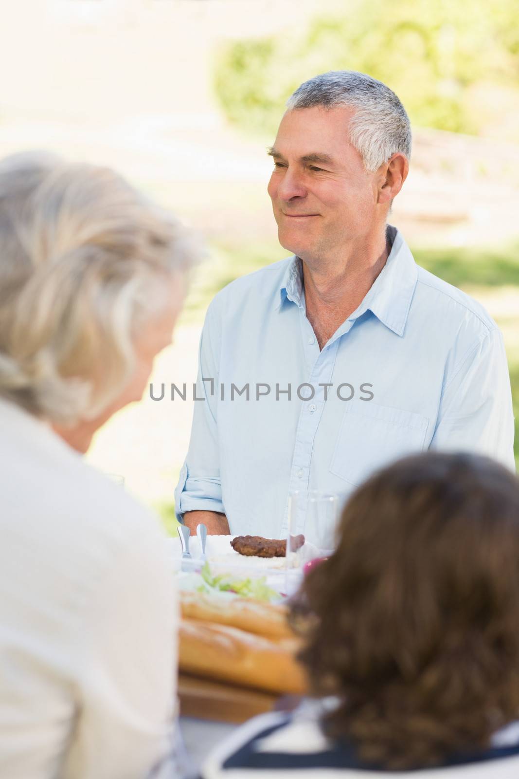 Smiling senior man sitting with family at outdoor dining table