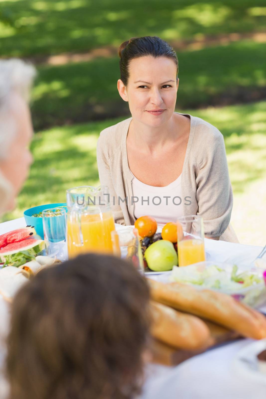 Smiling young woman sitting with family at outdoor dining table