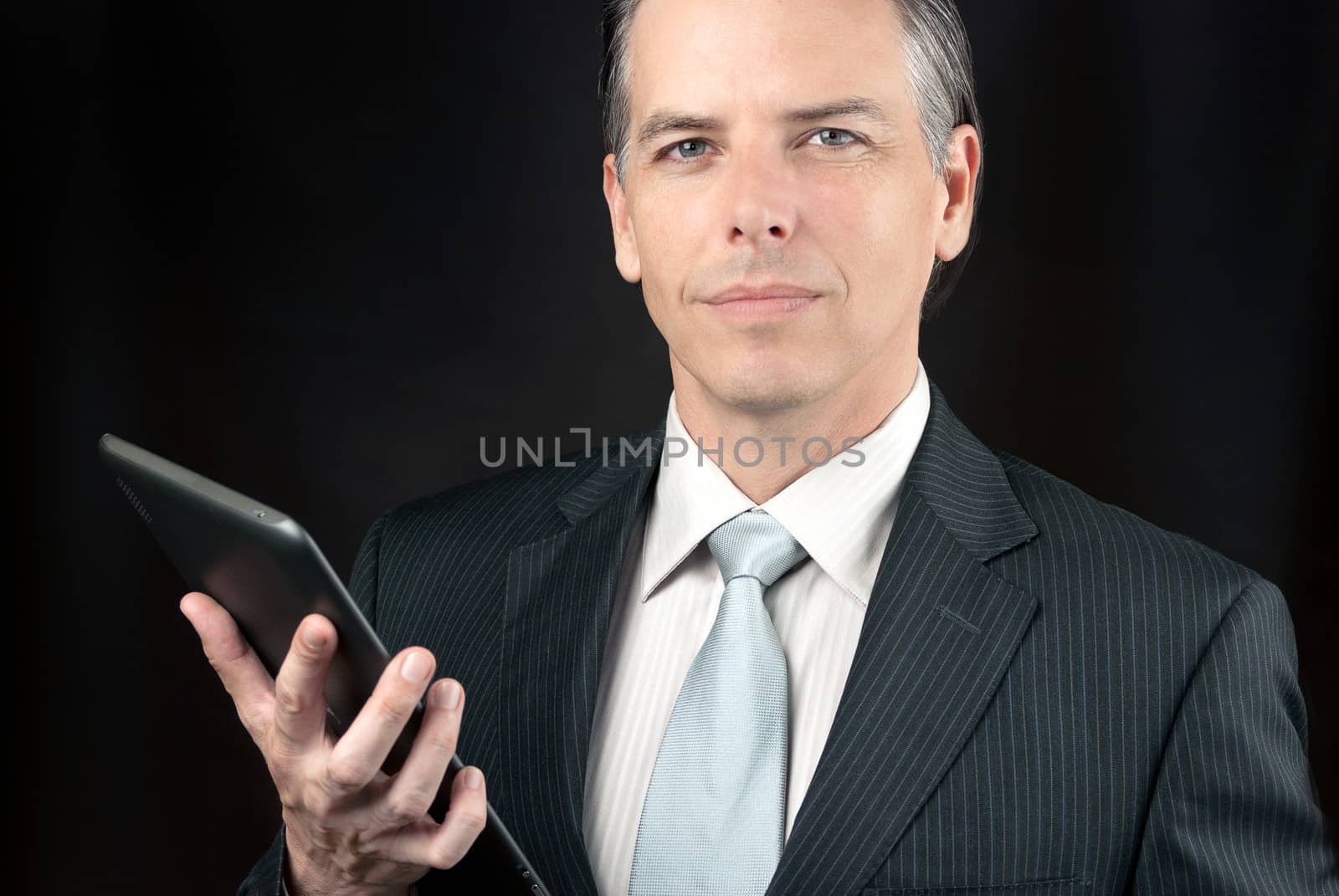 Close-up of a confident businessman holding his tablet.