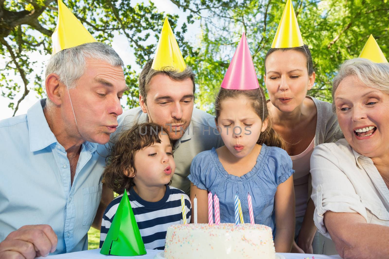 Extended family blowing cake outdoors by Wavebreakmedia