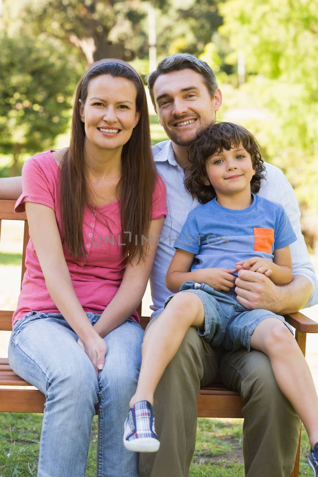 Smiling couple with son sitting on park bench by Wavebreakmedia