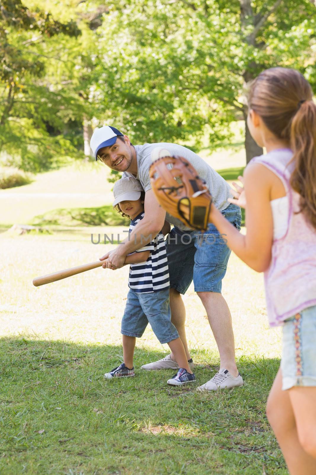 Family playing baseball in park by Wavebreakmedia