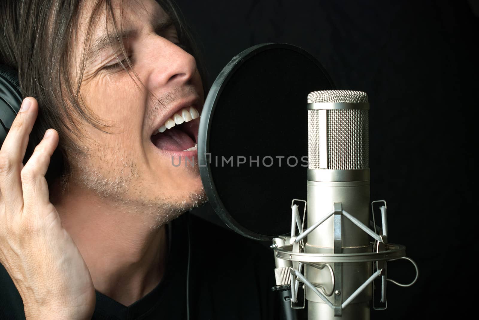 Close-up of a man singing into a condenser microphone.