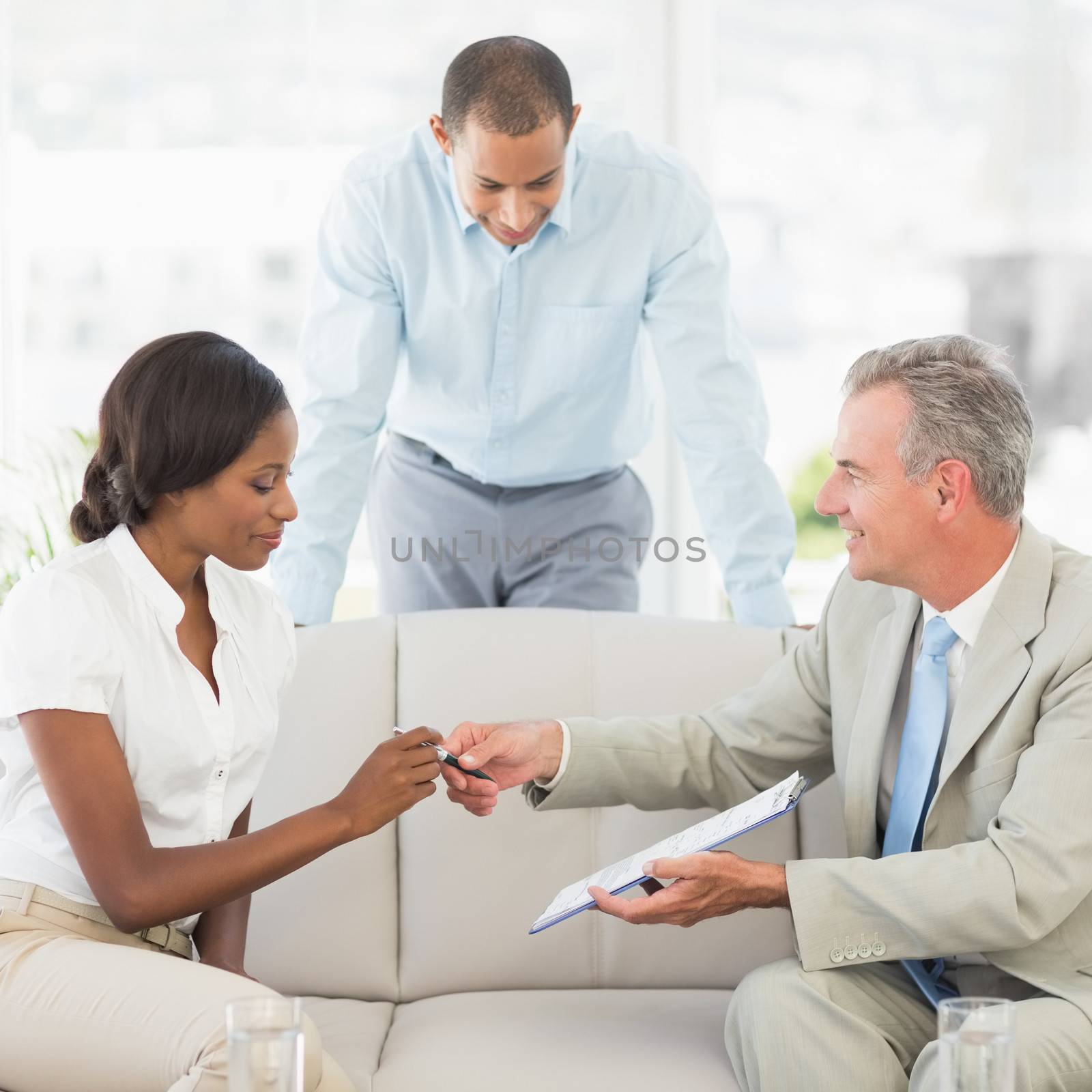 Salesman handing pen to client to sign the contract in the office