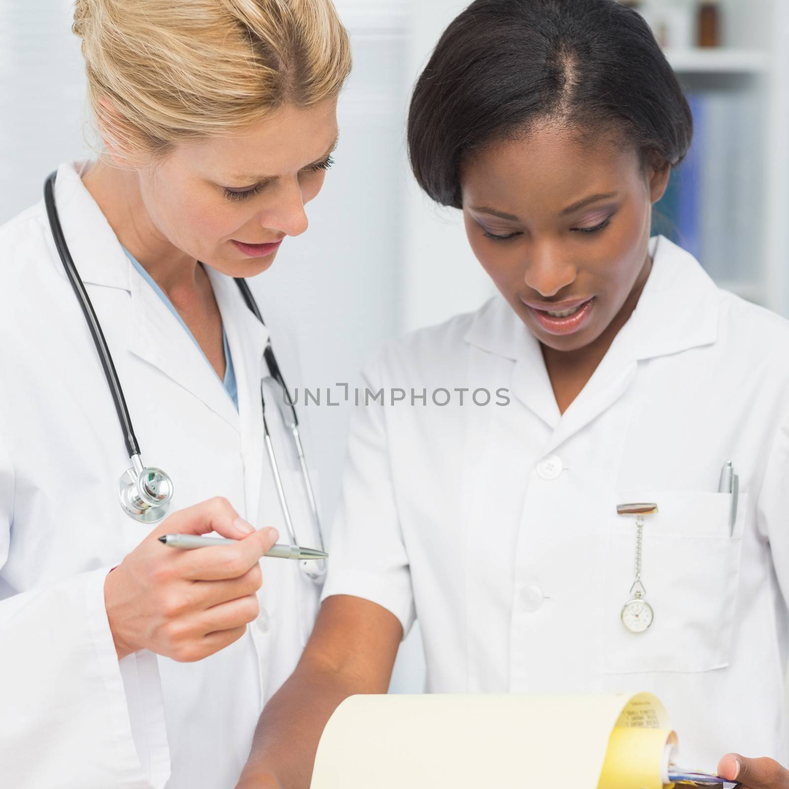 Cheerful doctor and nurse going over file together in an office at the hospital