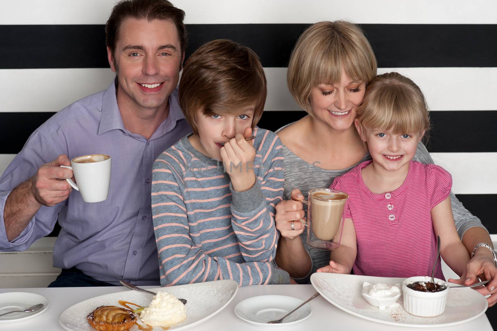 Family of four having great time in restaurant by stockyimages