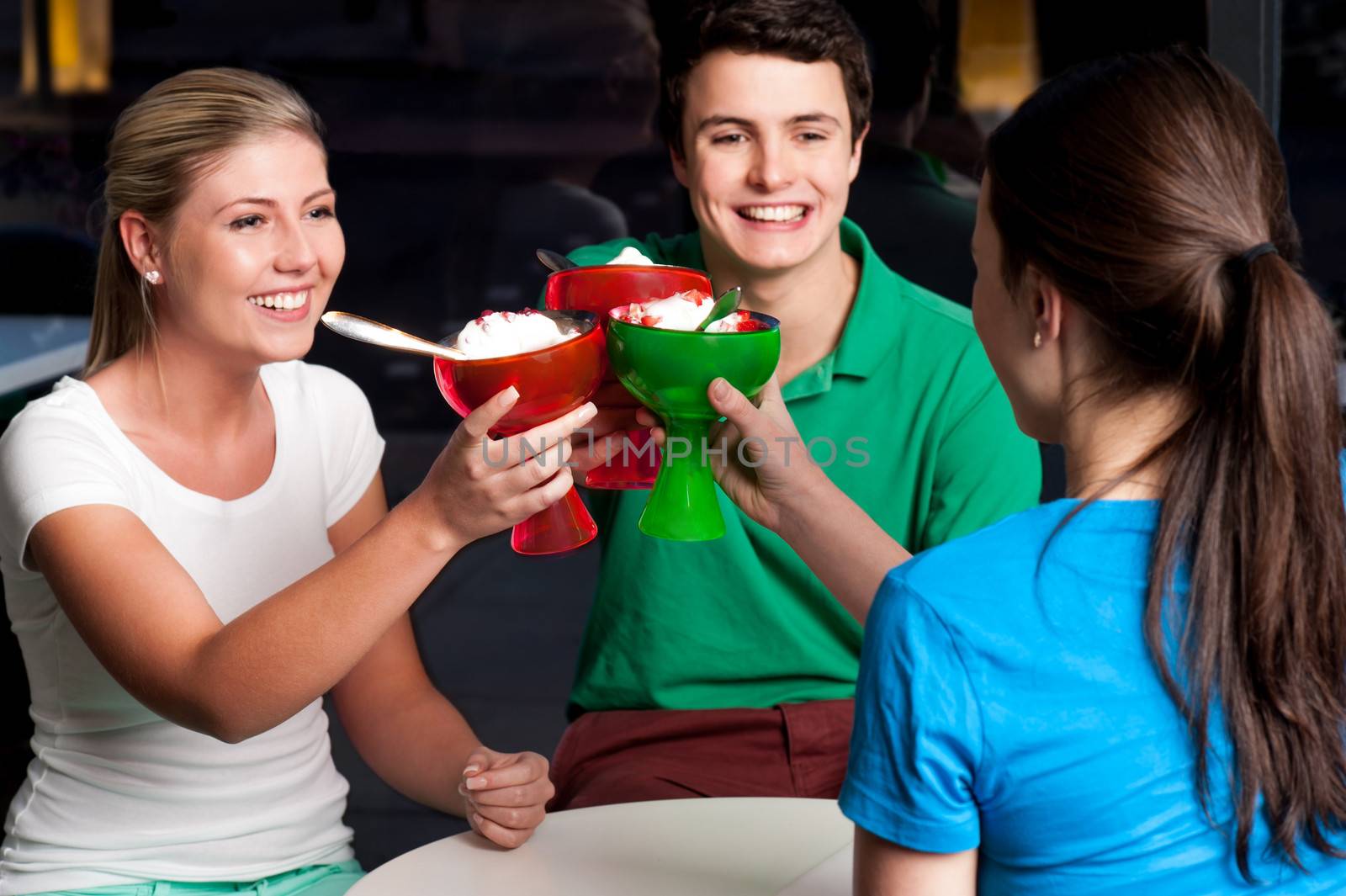 Three friends enjoying ice cream in a restaurant.