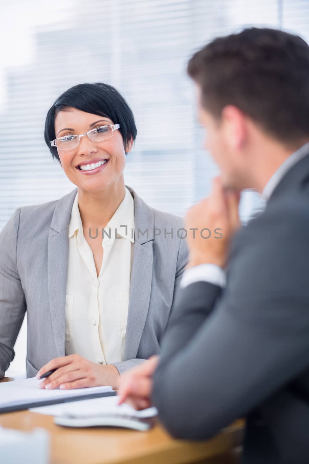 Smartly dressed young man and happy woman in a business meeting at office desk