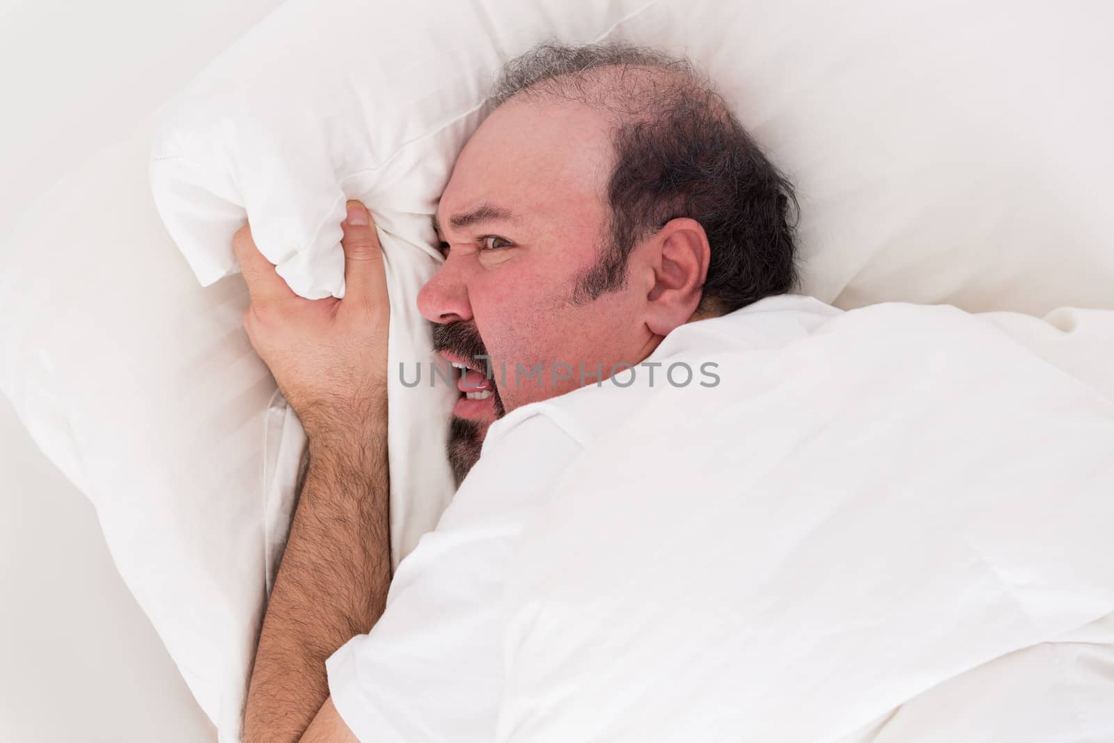 Insomniac clutching at his pillow in desperation as he balefully refuses to get up in the morning after a sleepless night