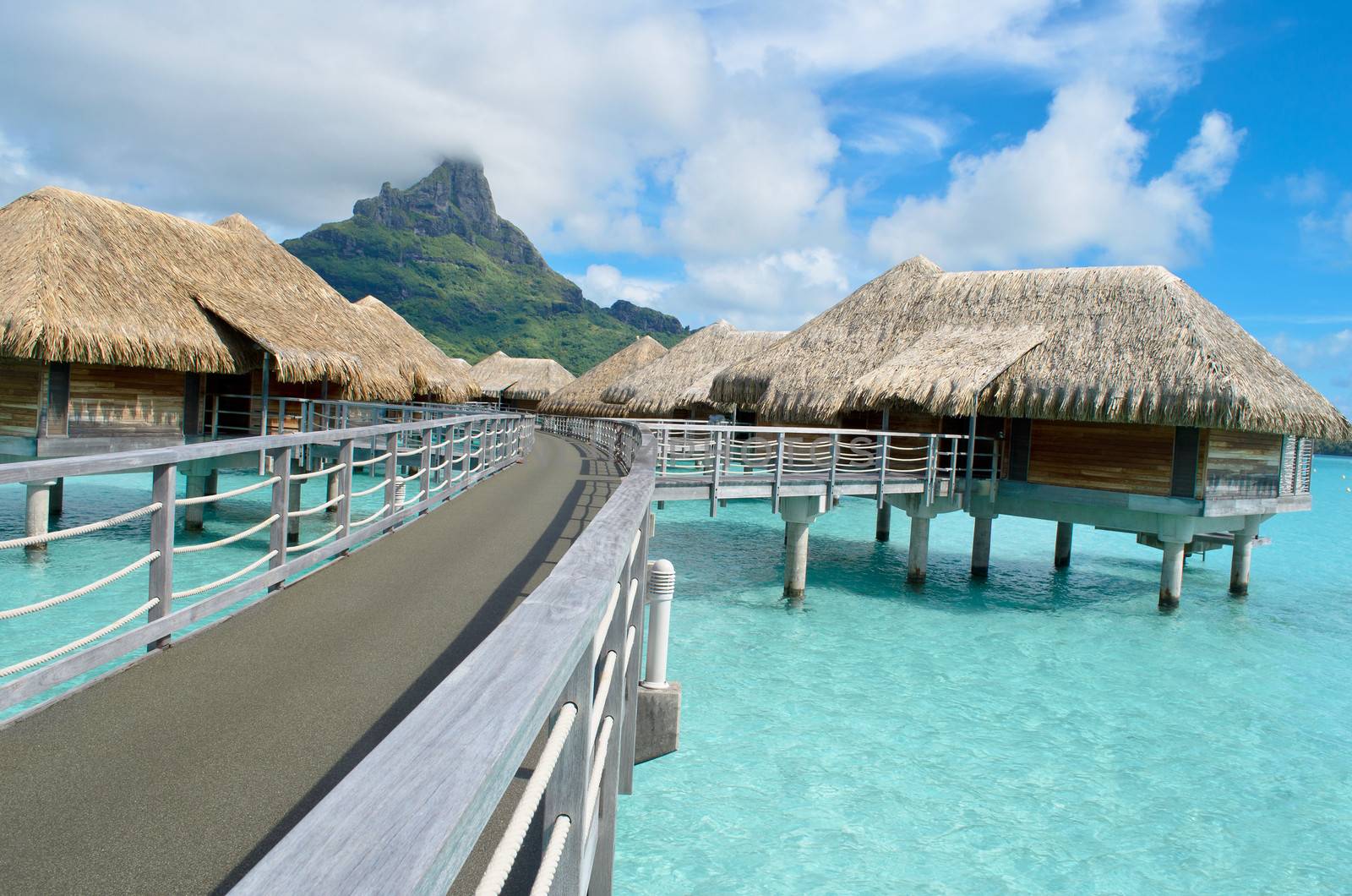 Luxury overwater bungalows in a vacation resort in the clear blue lagoon with a view on the tropical island of Bora Bora, near Tahiti, in French Polynesia.