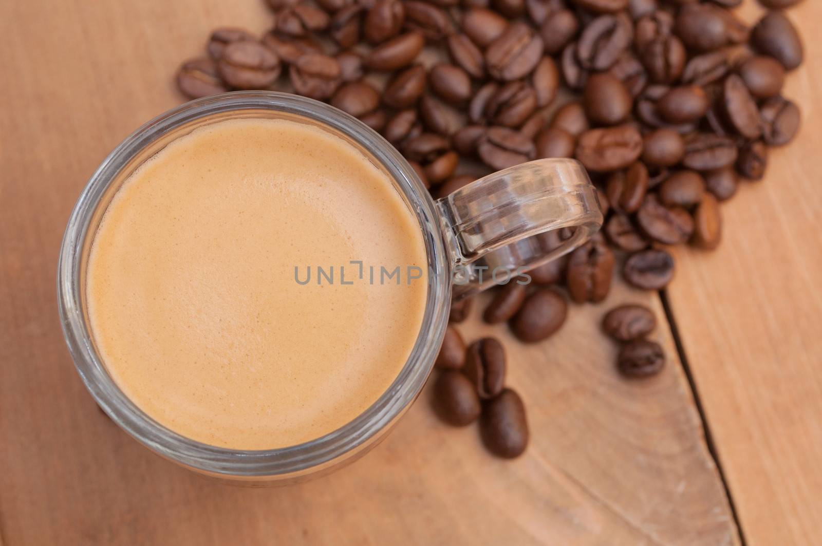 Top View of Glass Cup of Espresso Coffee on Wooden Table With Coffee Beans - Shallow Depth of Field