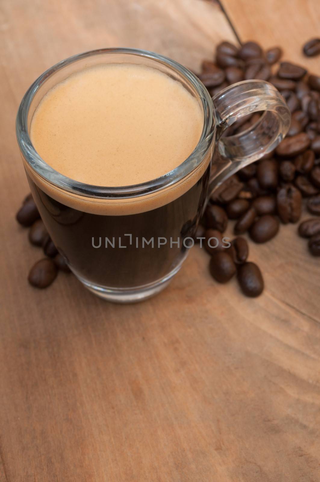 Glass Cup of Espresso Coffee on Wooden Table With Coffee Beans With Copyspace - Shallow Depth of Field