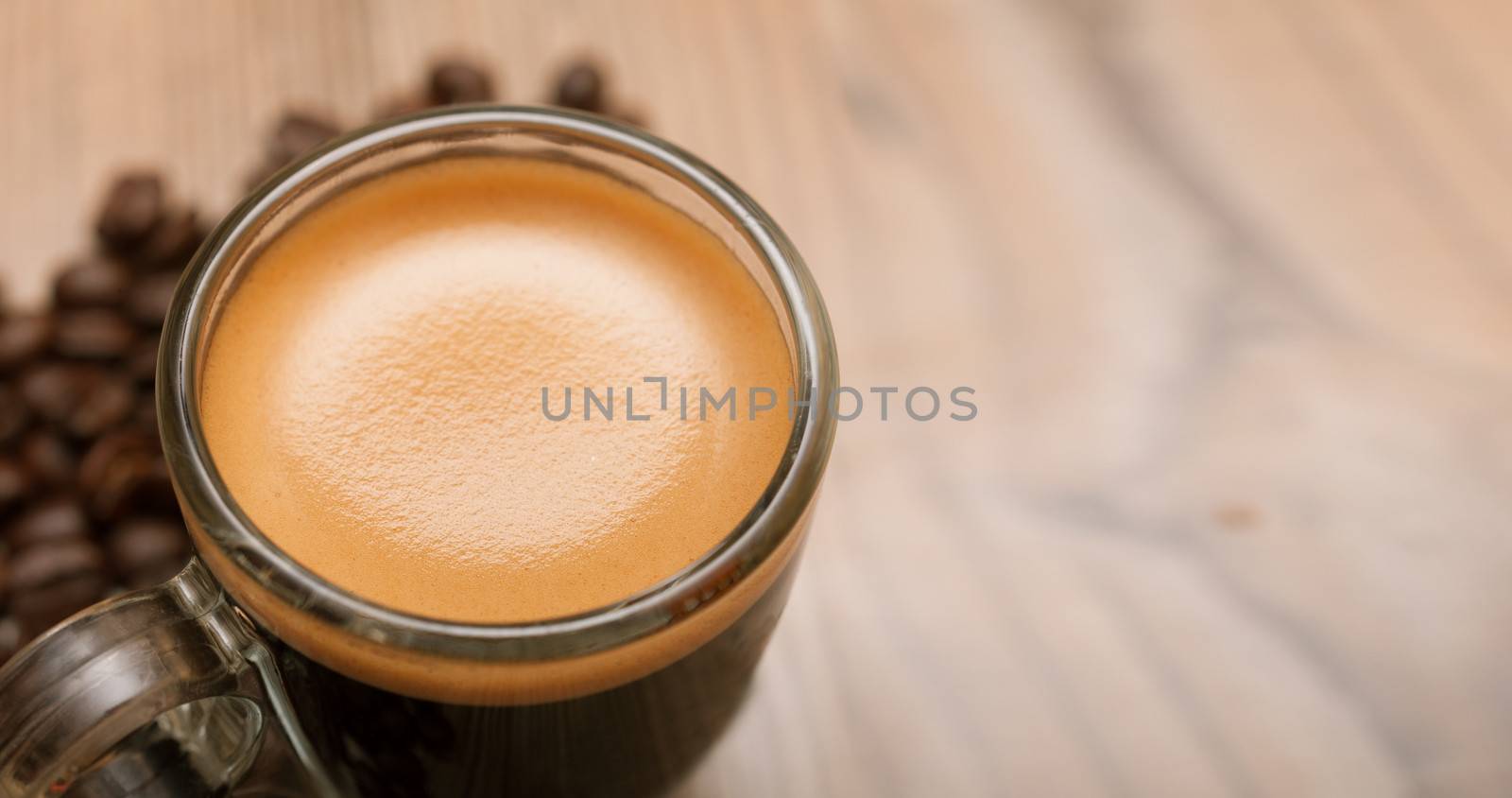 Glass Cup of Espresso Coffee on Wooden Table With Coffee Beans With Copyspace - Shallow Depth of Field