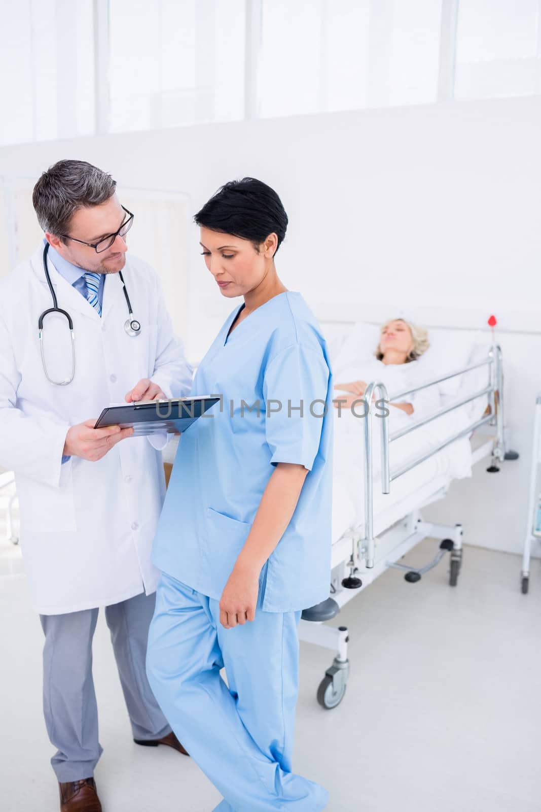 Doctors discussing reports with patient in hospital by Wavebreakmedia