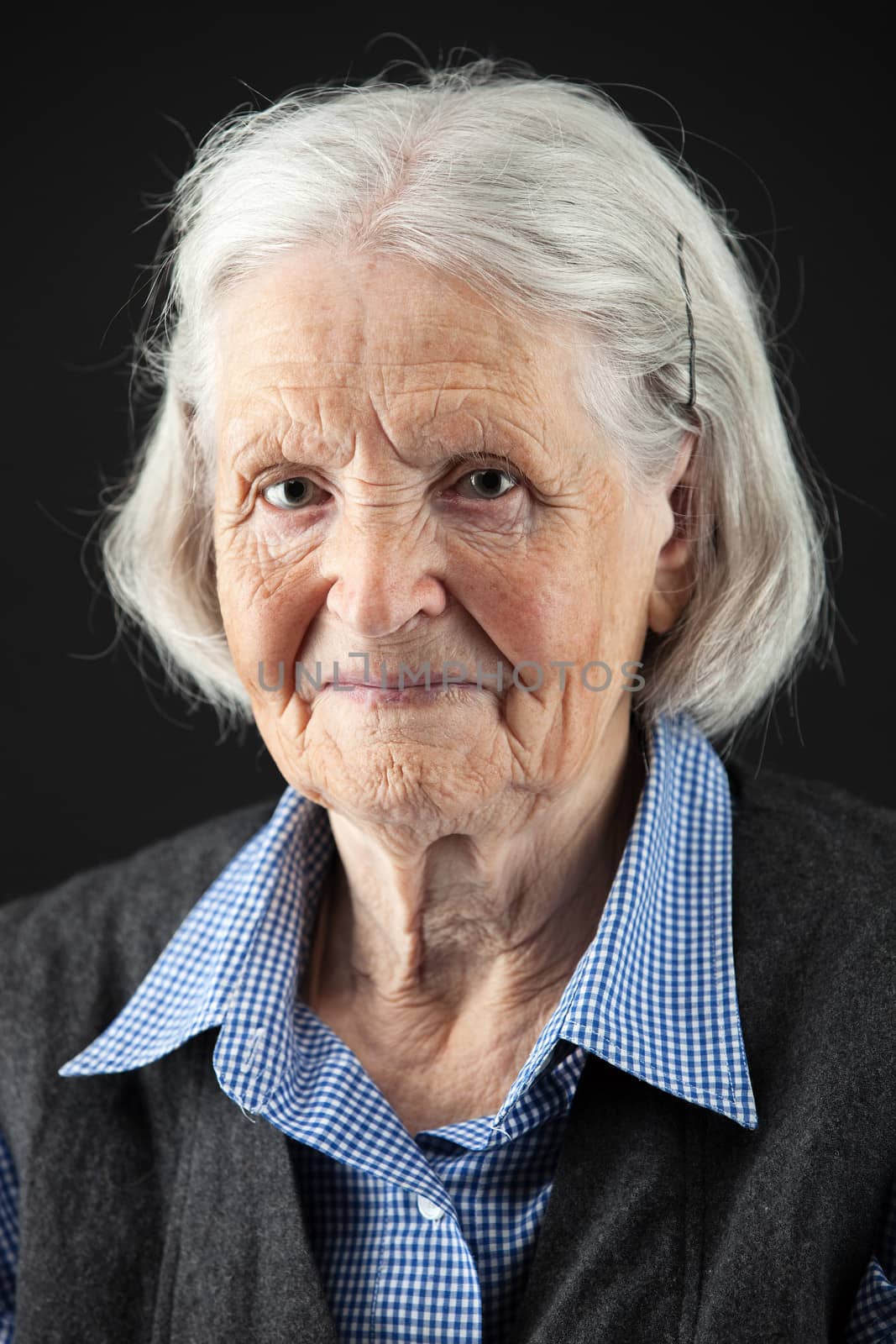 Portrait of a calm senior woman looking at the camera. Over black background.