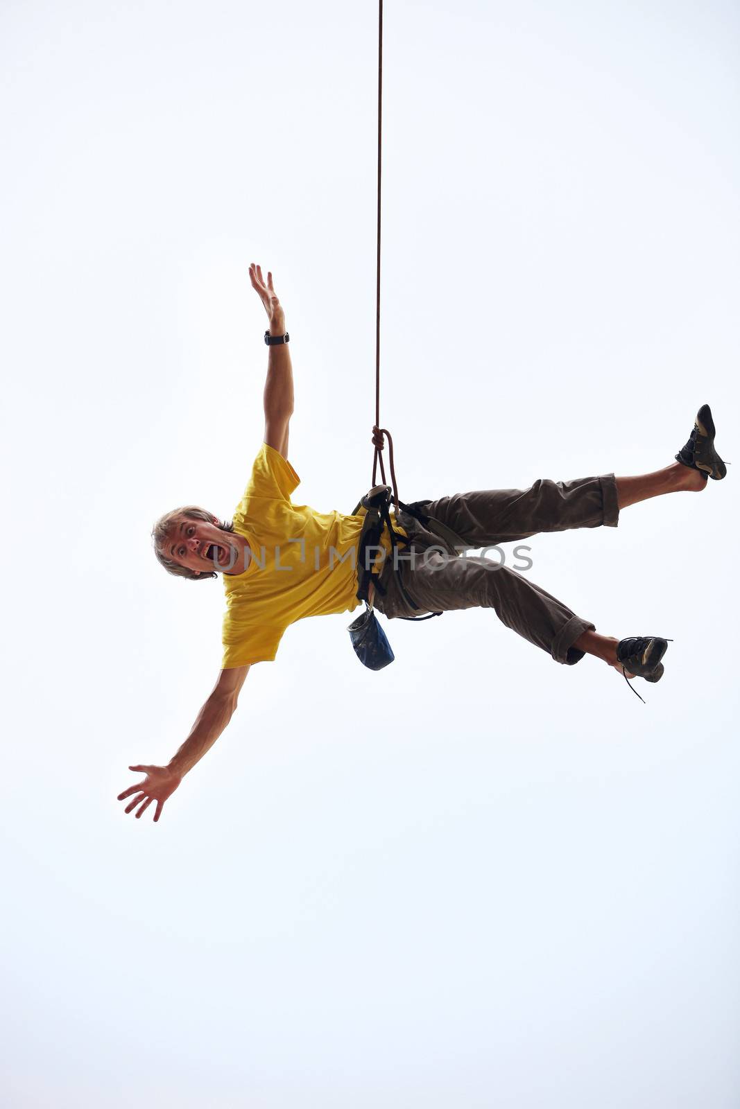 Happy rock climber hanging on rope by photobac