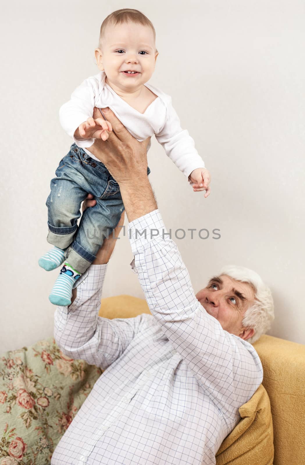Happy grandfather holding grandson while sitting on sofa