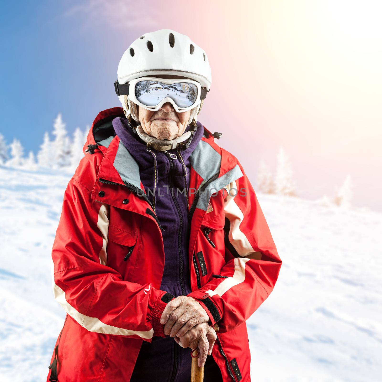 Senior woman in ski jacket and goggles outdoors. With path.