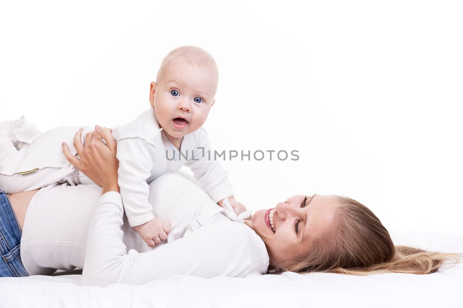 Young woman holding baby son while lying on back by photobac