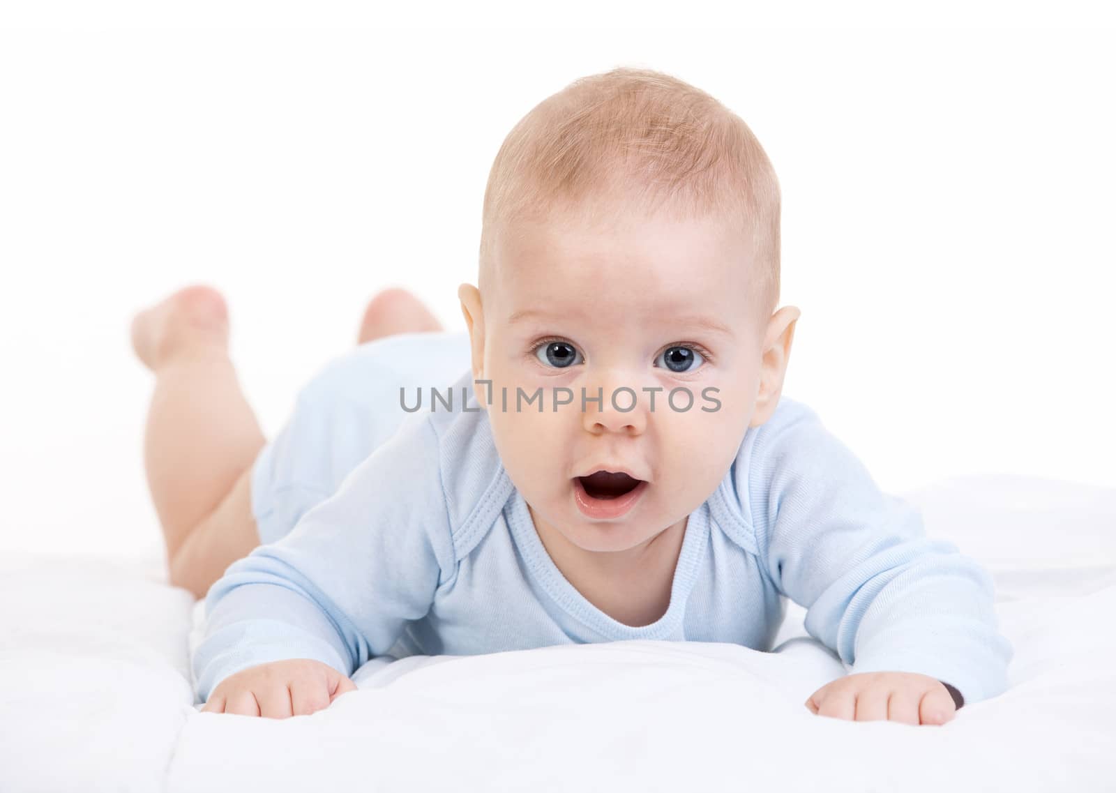 Little boy lying on stomach and looking at camera over white background