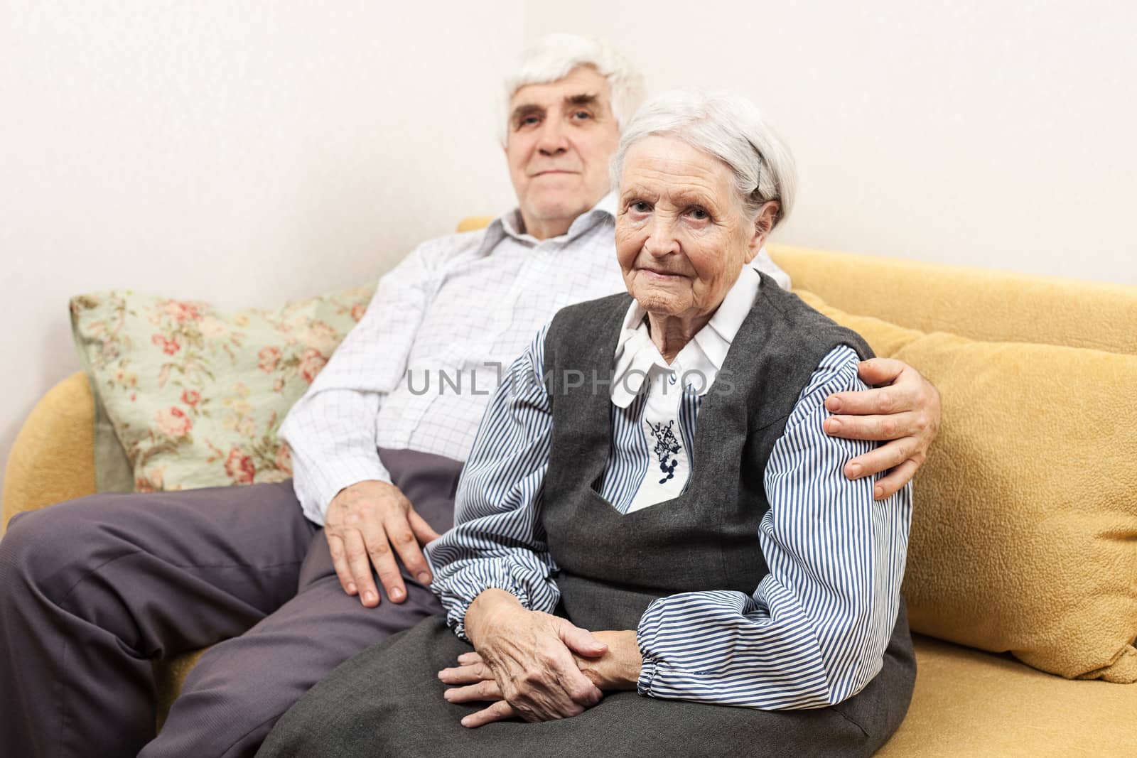 Mature man and senior woman sitting on sofa by photobac