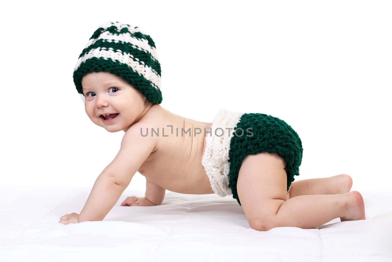 Happy baby boy in knitted hat crawling over white by photobac