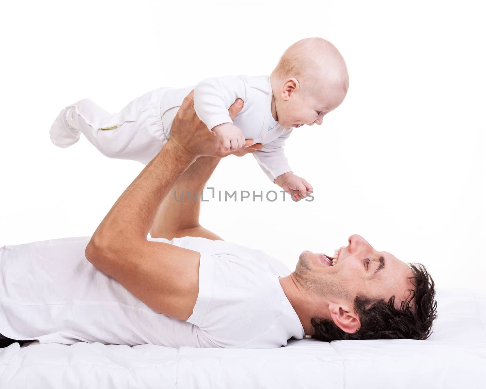 Happy young man holding baby son while lying on back