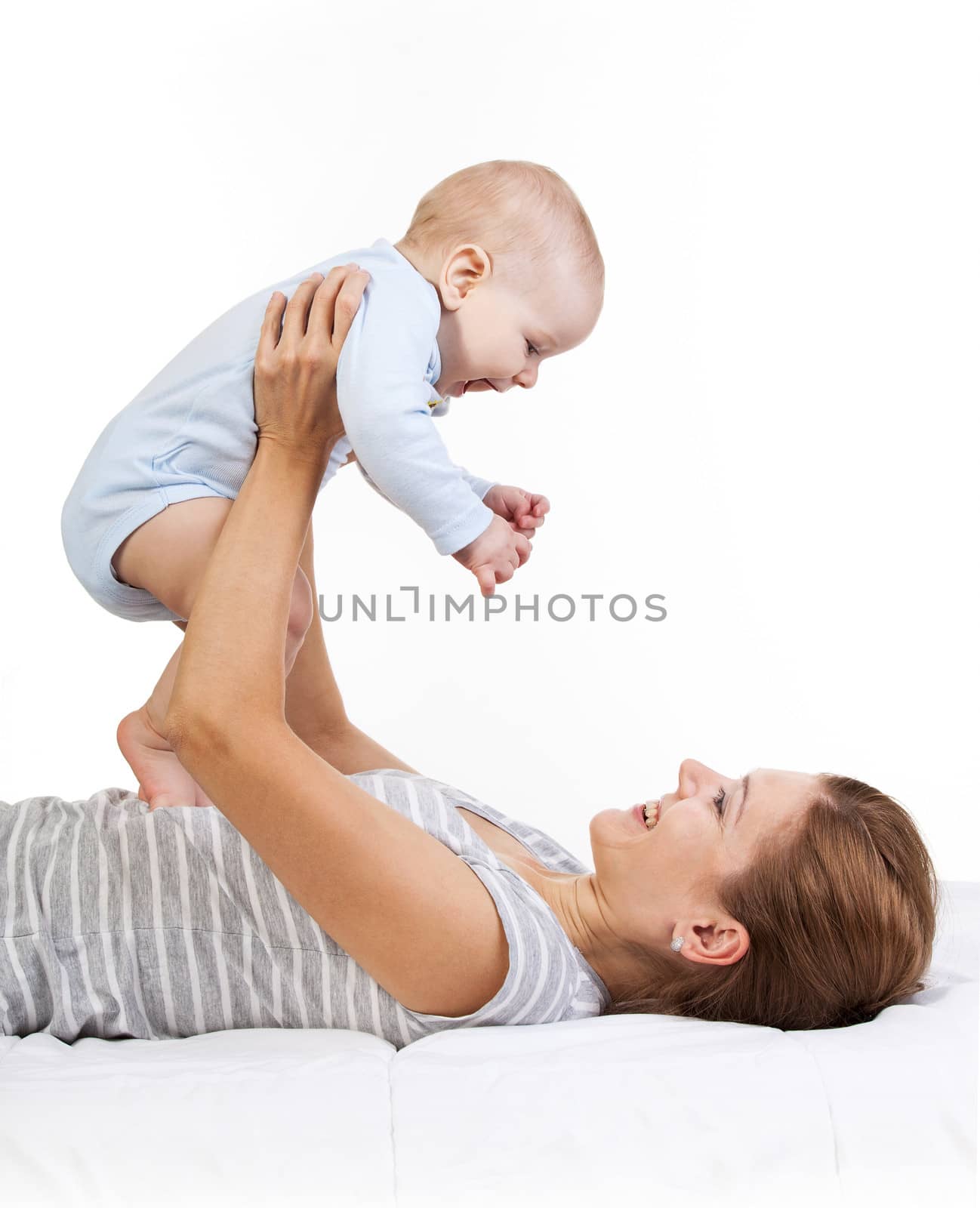 Happy woman holding baby son while lying on back by photobac