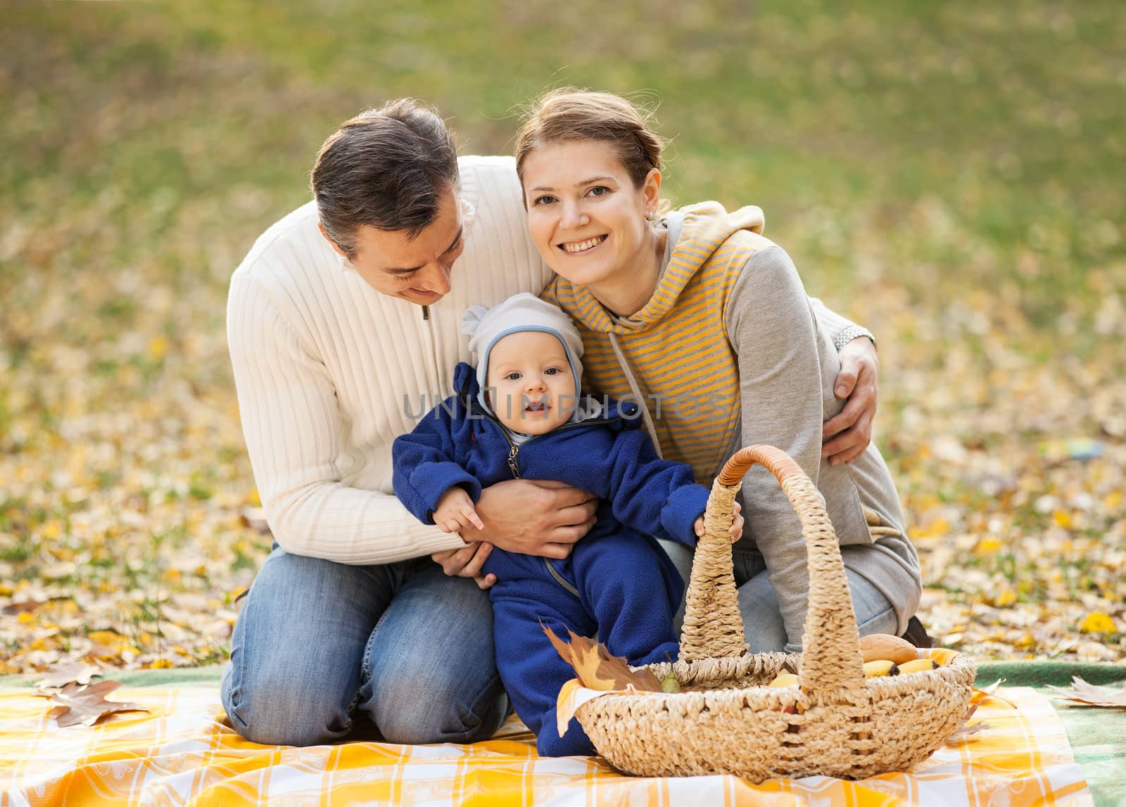 Young couple with baby boy on picnic in autumn park