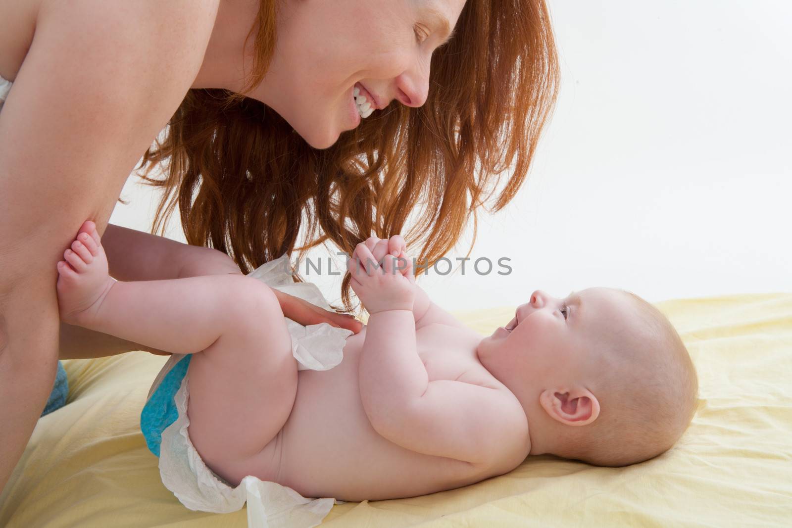Baby with mother diapering and playing smiling by lunamarina