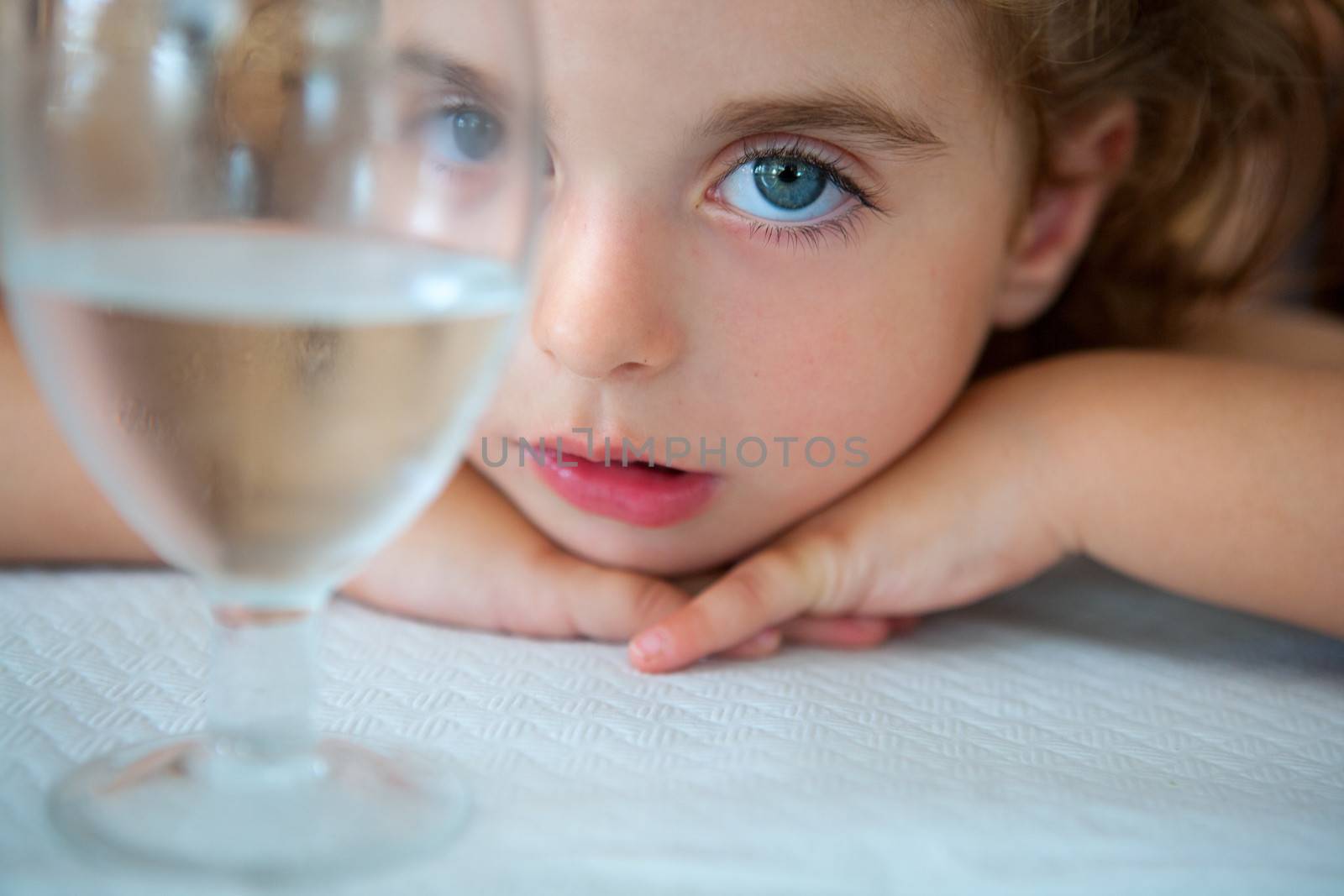 big blue eyes toddler girl looking at camera from a water cup by lunamarina