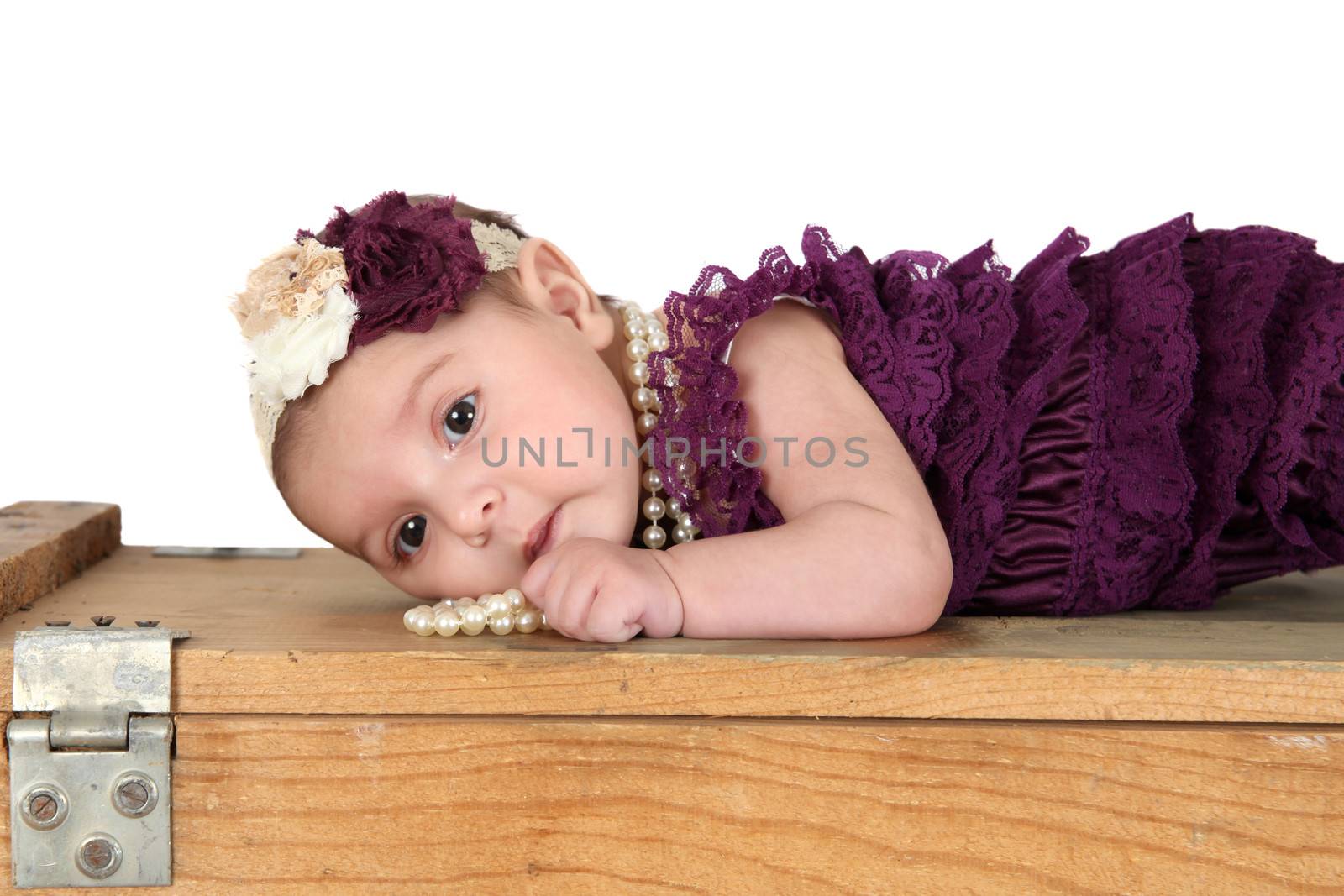 Brunette baby girl wearing a purple romper with pearls