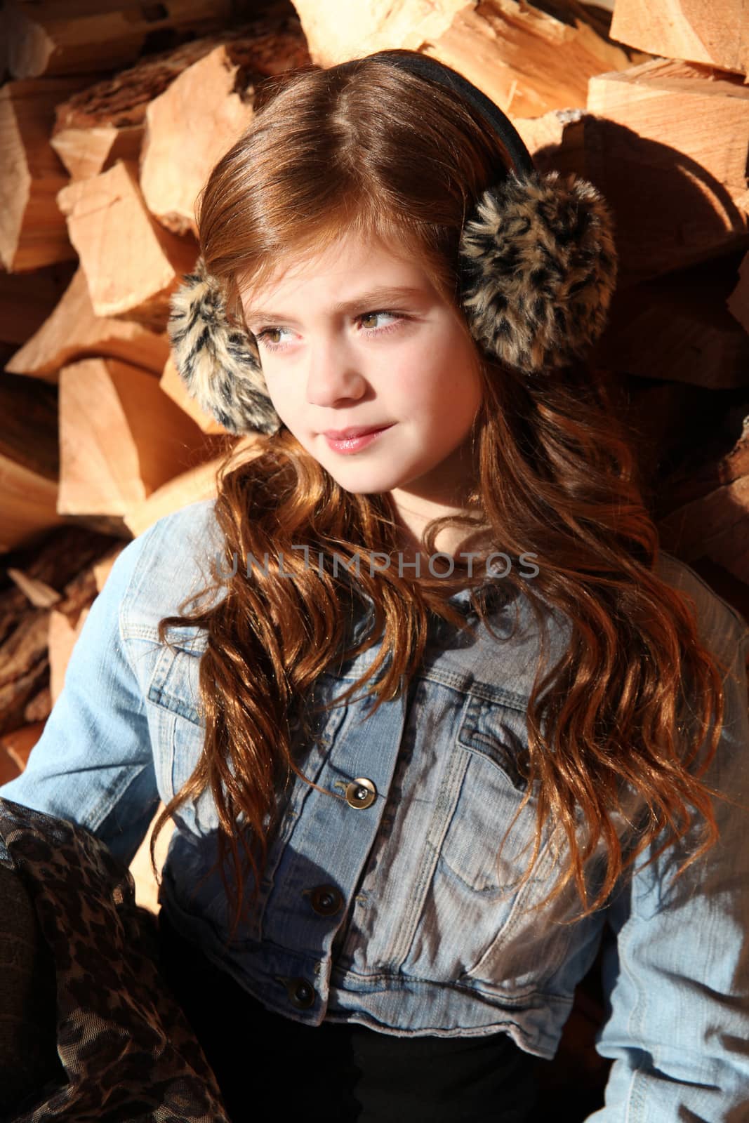 Red haired girl wearing earmuffs against wooden background