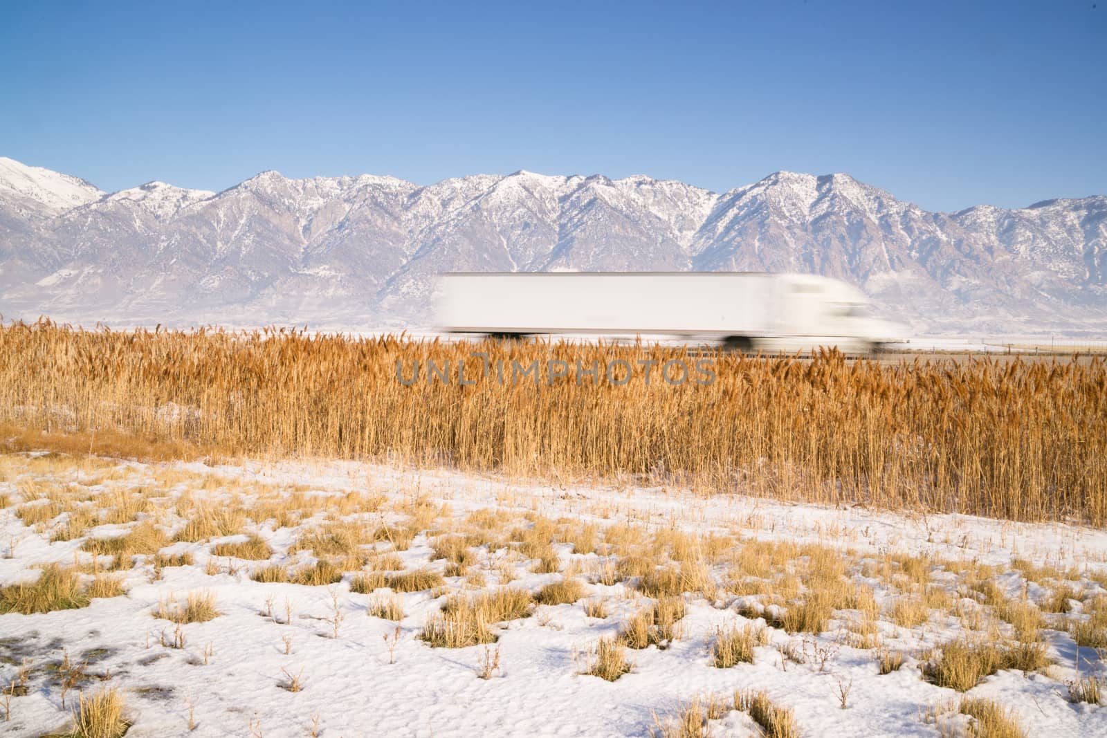 Snow Covered Mountains Behind Lakeside Highway PLant Growth Utah Landscape