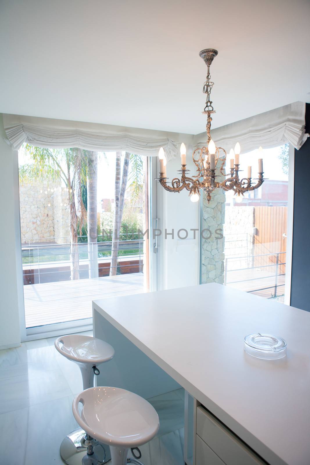 Modern white kitchen table with vintage chandelier and stools