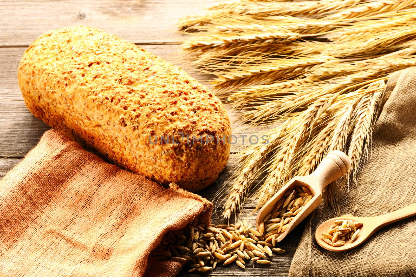 Rye spikelets and bread still life on wooden background by haveseen