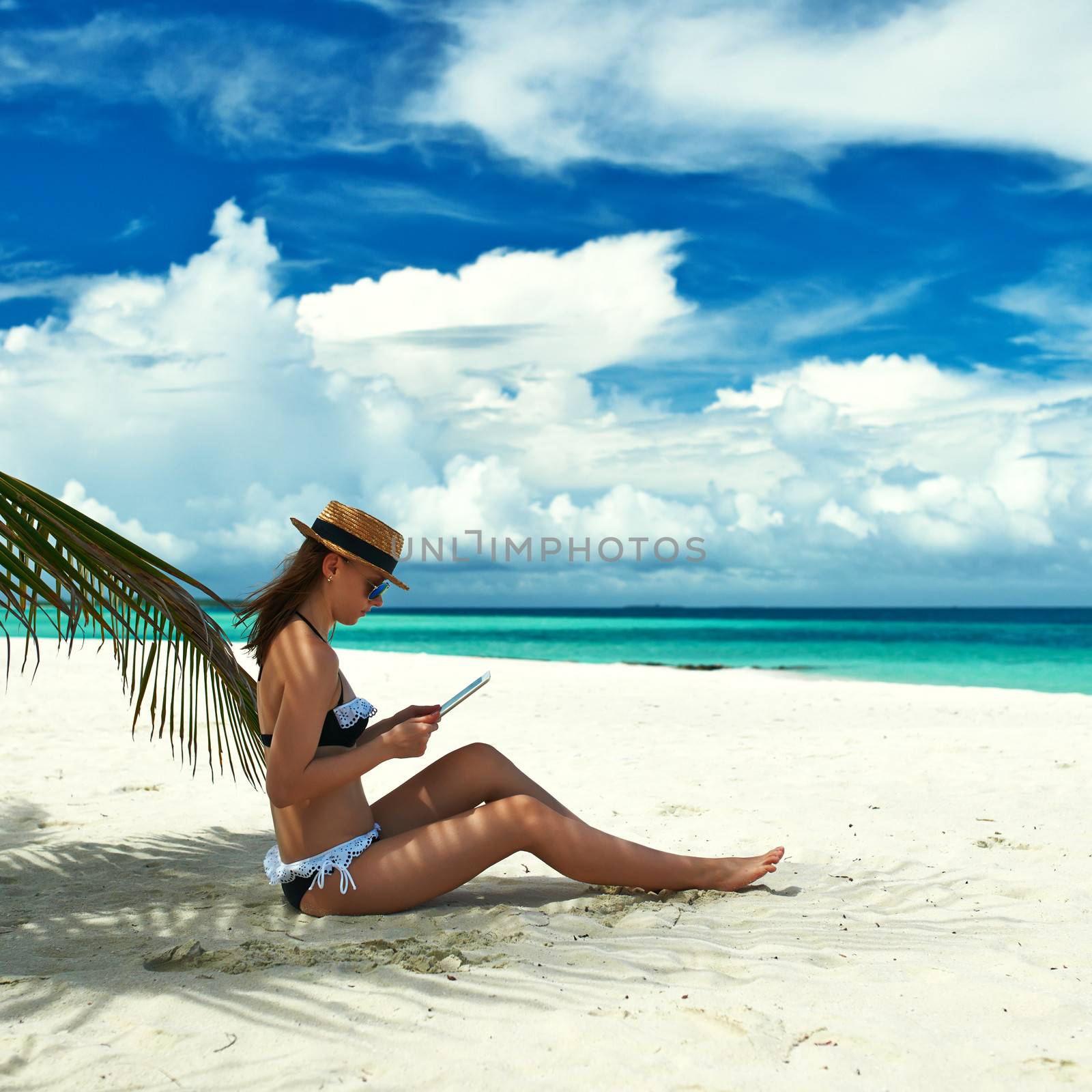 Young woman in hat with tablet pc at the beach