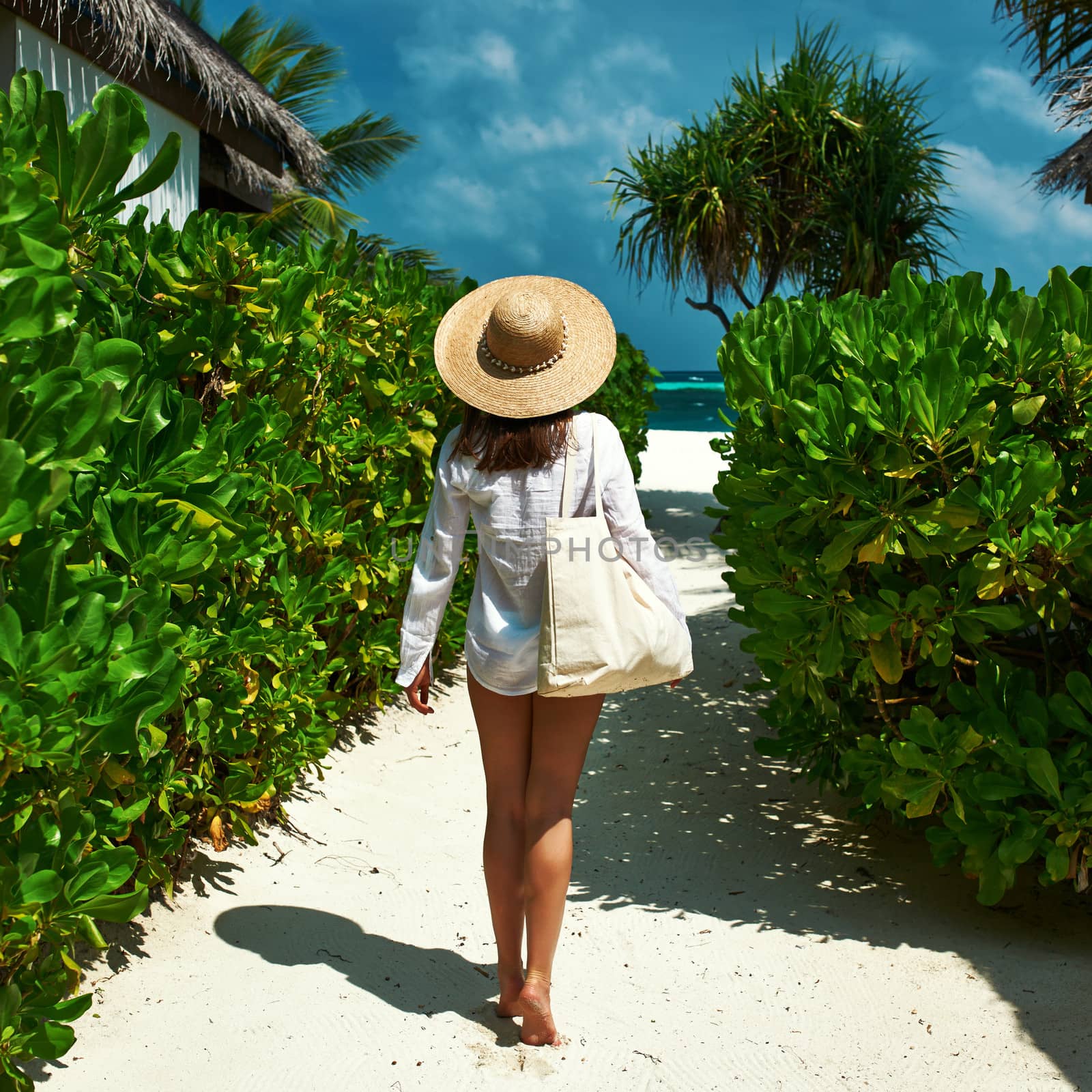 Woman with bag and sun hat going to beach by haveseen