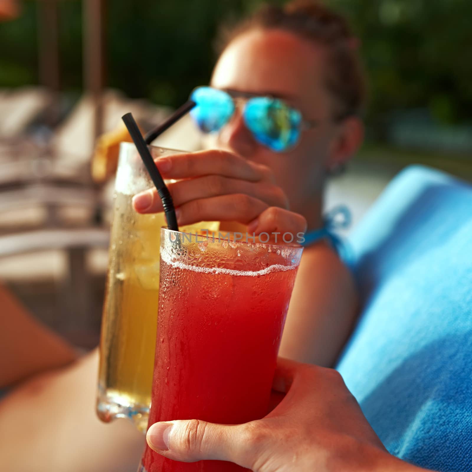 Couple clinking glasses with cocktails at poolside